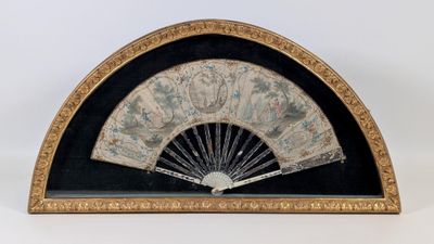un éventail noir et doré posé sur une table blanche