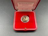 a small red box with a coin inside of it on a table