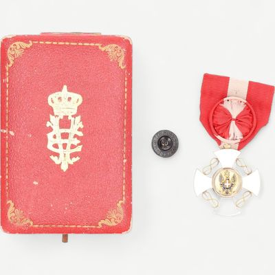 un livre rouge orné d'une médaille d'or et un livre rouge orné d'un ruban rouge