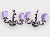 three purple lamps on a white wall with purple shades