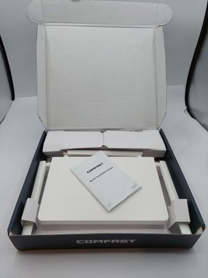 une boîte ouverte contenant un ordinateur portable blanc, posée sur une table blanche