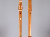 pair of wooden flutes on a clear stand against a gray background