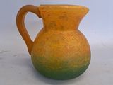 un vase jaune et vert posé sur une surface blanche