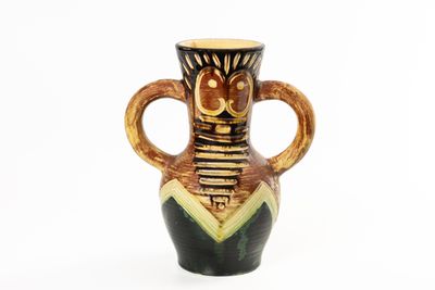 a brown and black vase with a face on it