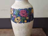 a white vase with flowers painted on it on a wooden table