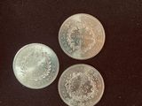 three silver coins sitting on top of a black surface