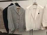 three suits hanging on a rack in a clothing store