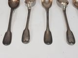 six silver spoons are lined up on a white surface