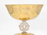 un bol en verre jaune avec un socle doré sur fond blanc