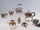 de nombreux modèles différents de théières et de tasses en argent sur la table