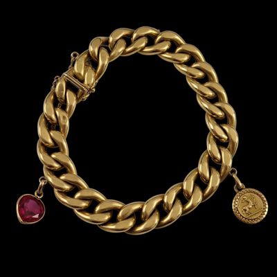 a gold bracelet with a ruby stone charm