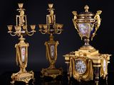 three gold and blue vases and a clock on a black surface