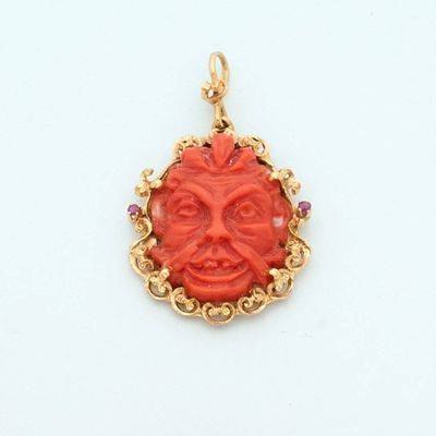 an image of a red and gold pendant with a face in the center