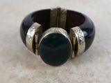 a close up of a ring with a green stone on it