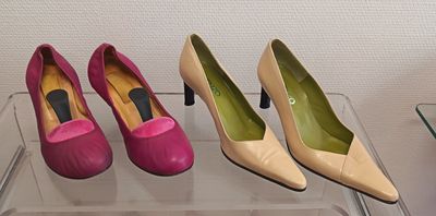 three pairs of pink and yellow high heeled shoes on a clear shelf