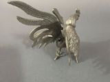 a silver figurine of a bird on a table