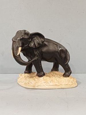 statue of an elephant with tusks and tusks standing on a rock