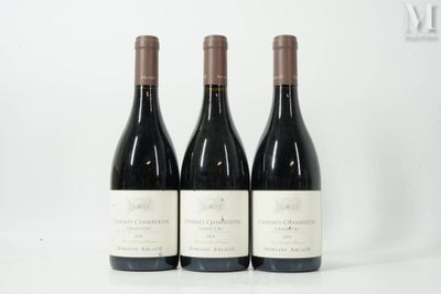 trois bouteilles de vin rouge sont alignées sur une surface blanche