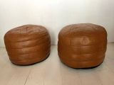 two brown leather ottomans sitting on top of a wooden floor