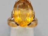 a close up of a yellow sapphire ring on a white surface