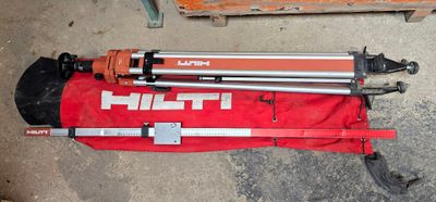 a tripod sitting on a red bag next to a pair of tools