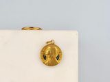 a gold coin with a face on it sitting on a white surface