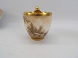 a picture of a gold and white vase with a tree scene on it