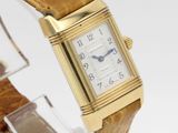 a gold watch with a brown leather band on a clear stand