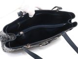 someone is holding a black purse with a white cat in it