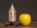 a yellow apple next to a silver rocket on a wooden table