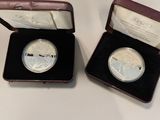 two silver coins are in a case on a table