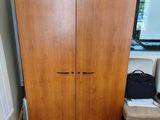 a wooden cabinet in the corner of a room next to a window