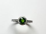 gros plan d'une bague avec une pierre verte entourée de diamants