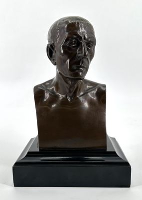 un buste en bronze représentant un homme, posé sur un socle noir