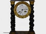 a black and gold clock on a stand on a white background