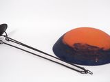 an orange and blue bowl with a black handle on a white surface