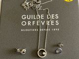 Le livre est ouvert et on y voit un collier et des boucles d'oreilles en argent.