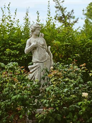 une statue au milieu d'un jardin, entourée de buissons