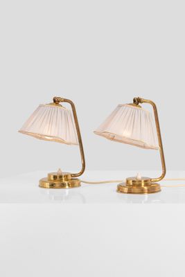 a pair of brass table lamps with plea lampshads
