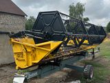 une machine jaune et noire posée au milieu d'un champ de terre battue
