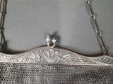 an old silver purse hanging on a wall with a chain around it