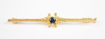 an image of a gold broochle with a blue stone