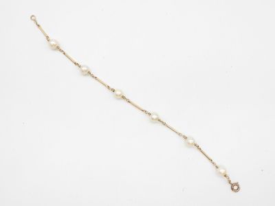 un bracelet en or et perles orné d'une petite breloque en forme de perle