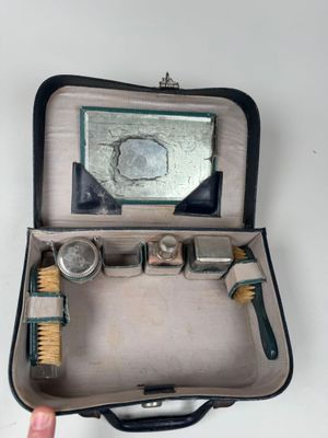 une personne tenant une valise dans laquelle se trouvent une brosse et un miroir