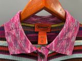 La chemise est rayée et est suspendue à un cintre en bois.