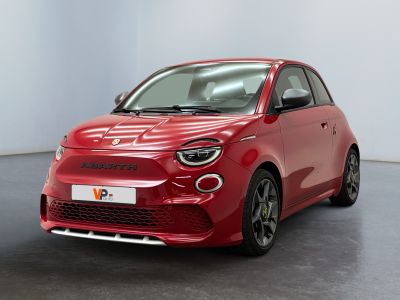 La Smart rouge est garée dans une pièce aux murs blancs.