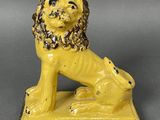 une figurine de lion jaune posée sur un socle noir
