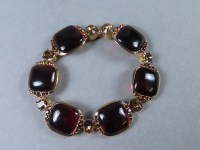 un gros plan d'un bracelet orné de pierres rouges