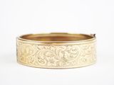a close up of a gold bracelet on a white surface