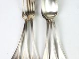 quatre cuillères en argent et une fourchette sur une table blanche